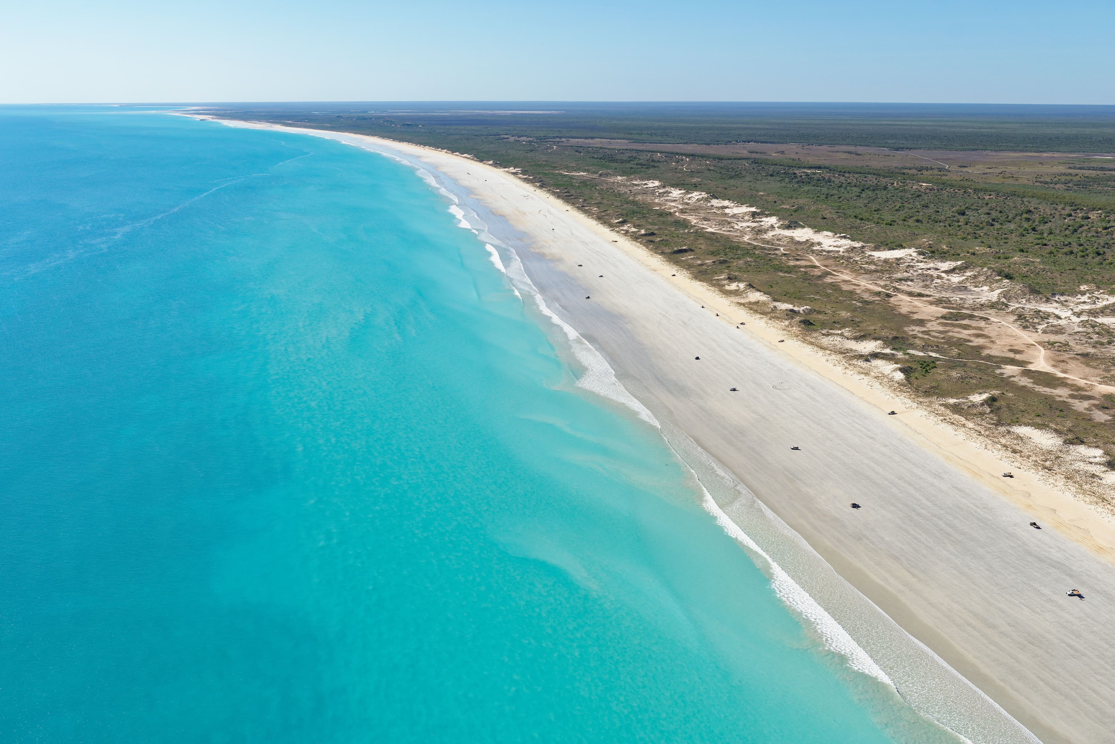 An aerial view of Cable Beach in Broome showcases the long stretch of pristine white sand meeting the vibrant blue waters of the Indian Ocean